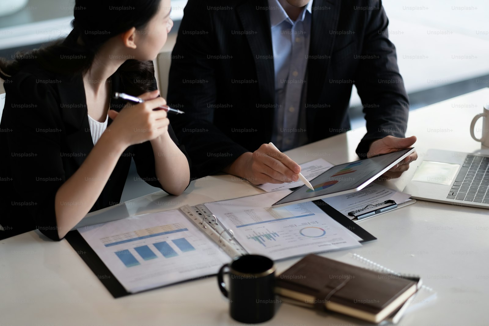 An adviser and clients working through a plan comparison on paper and tablet