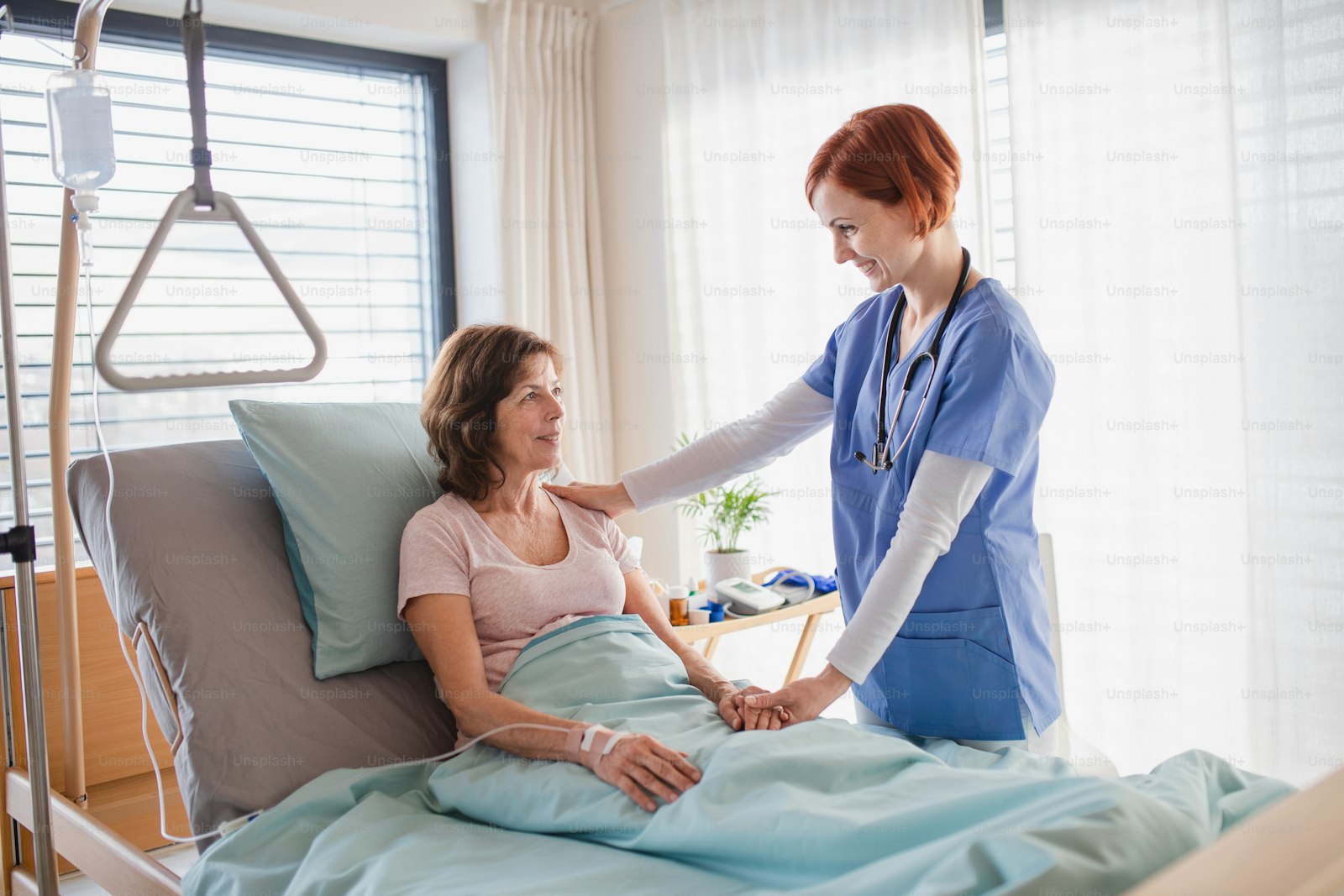 A doctor examining a patient at the bedside on a hospital ward