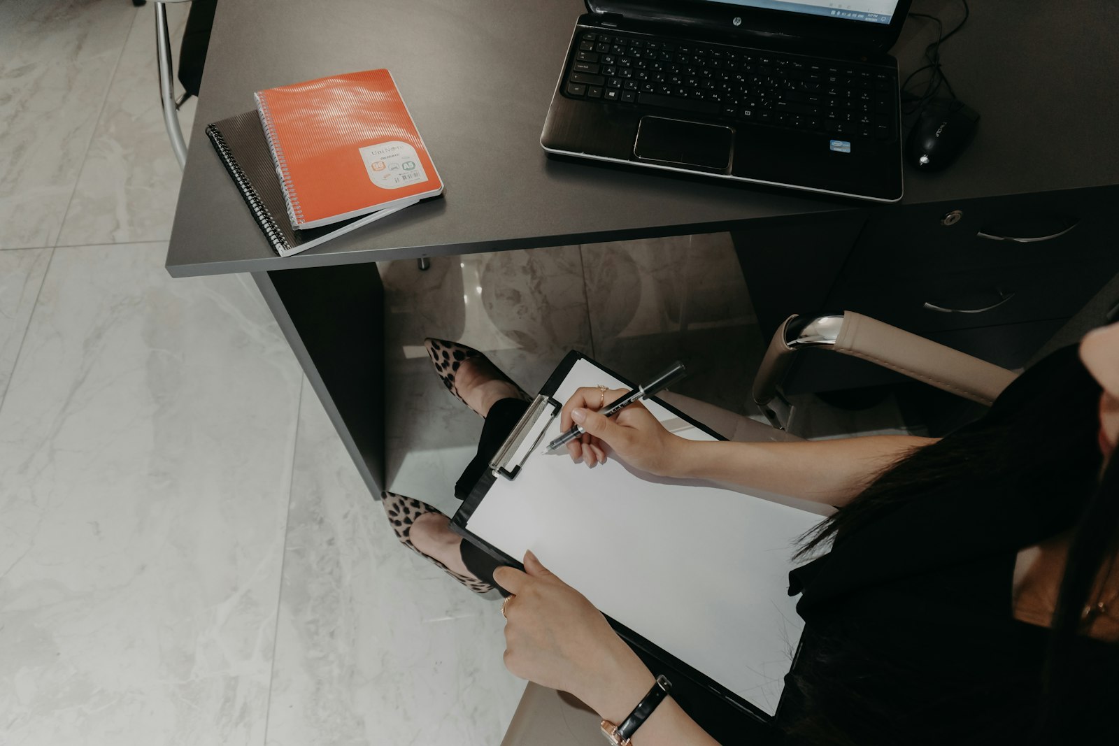 A person working through a checklist on a clipboard beside a laptop