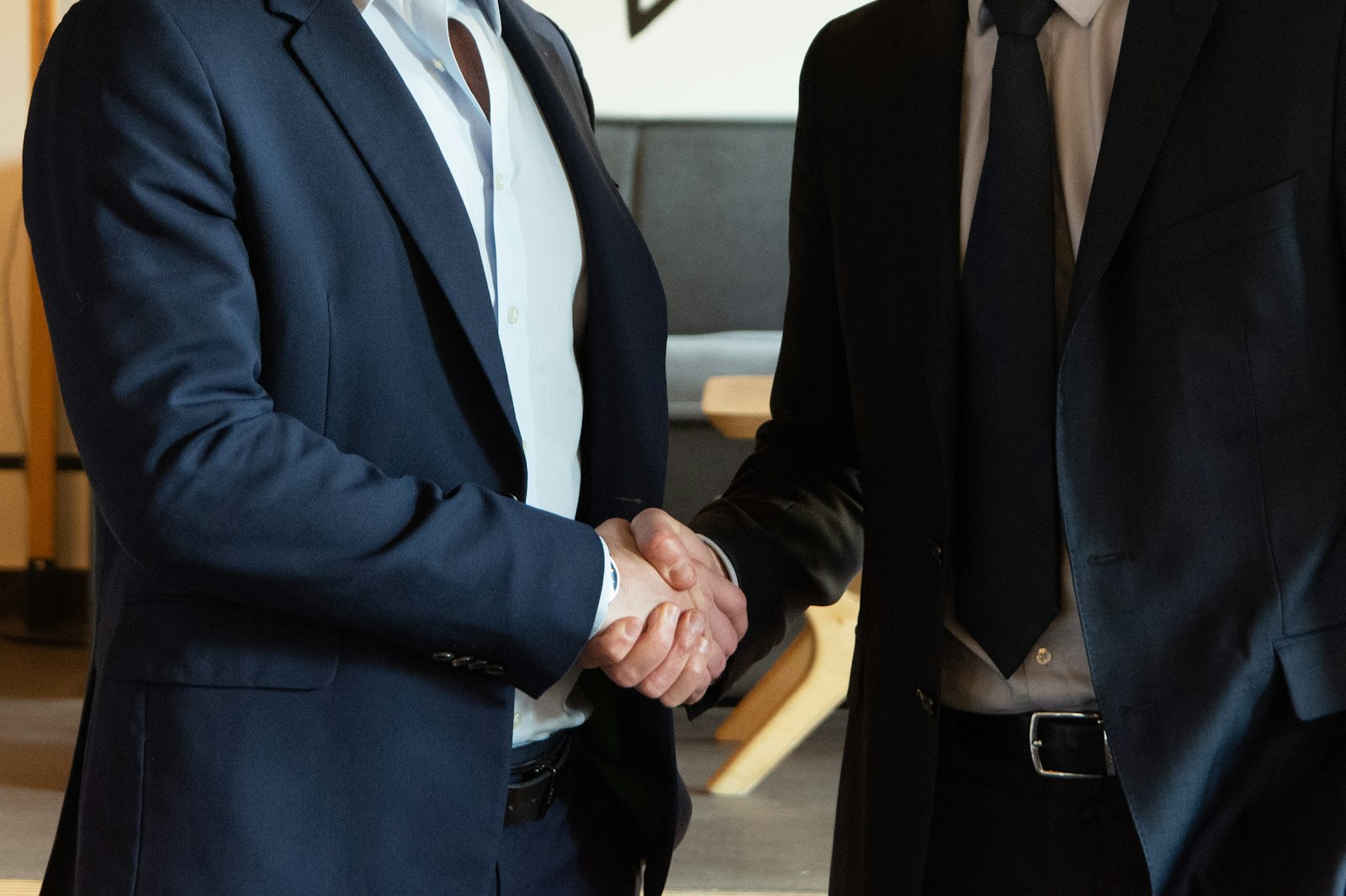 Two people shaking hands across a desk in agreement