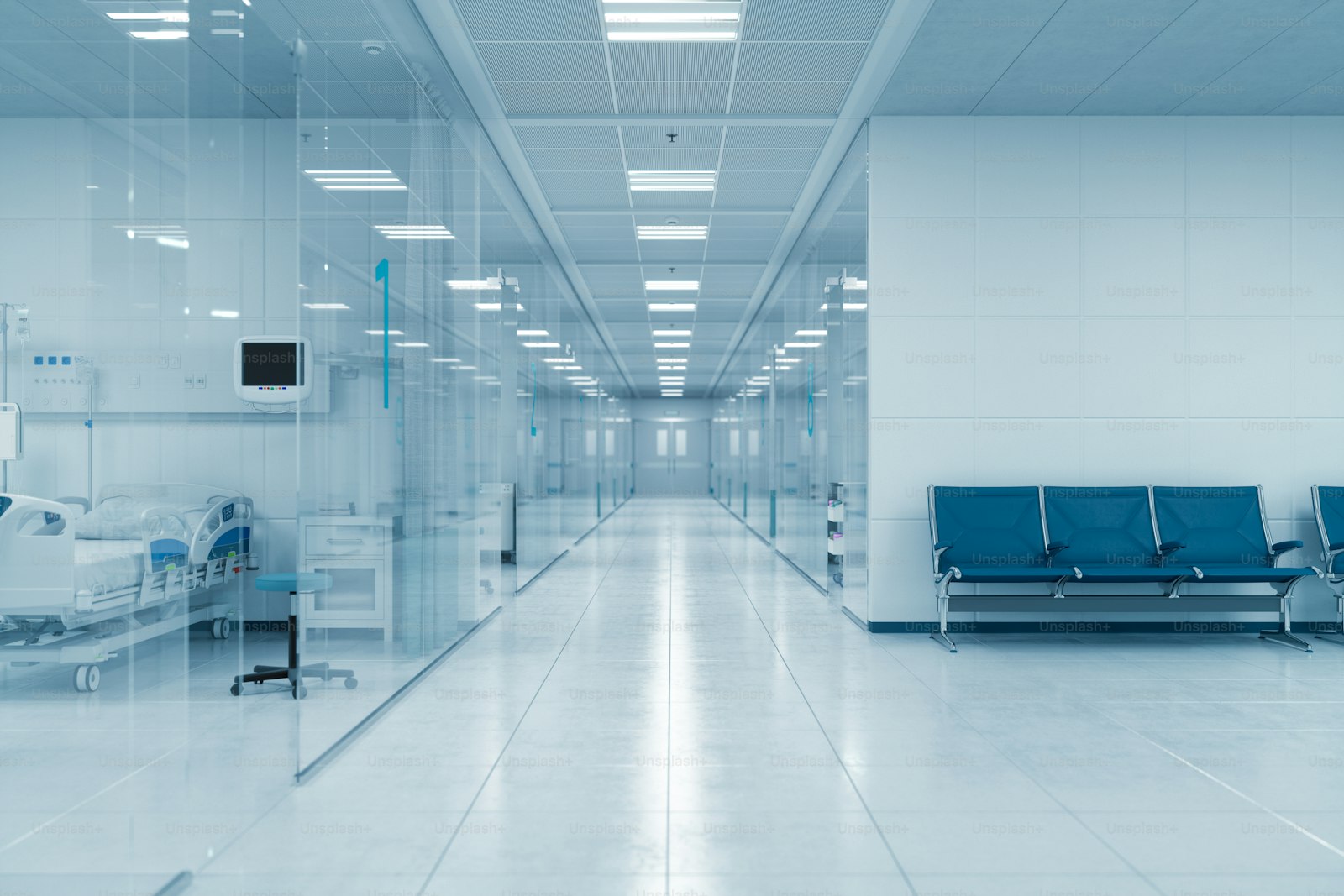 A glass-walled hospital corridor with a patient bed and waiting chairs