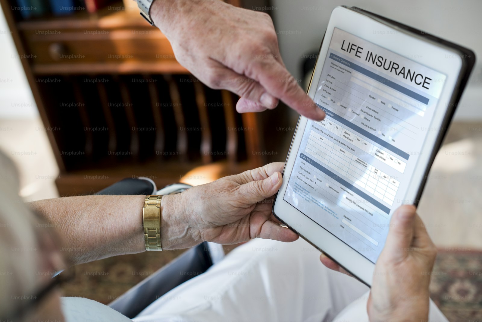 An adviser pointing out a benefit on a policy schedule shown on a tablet