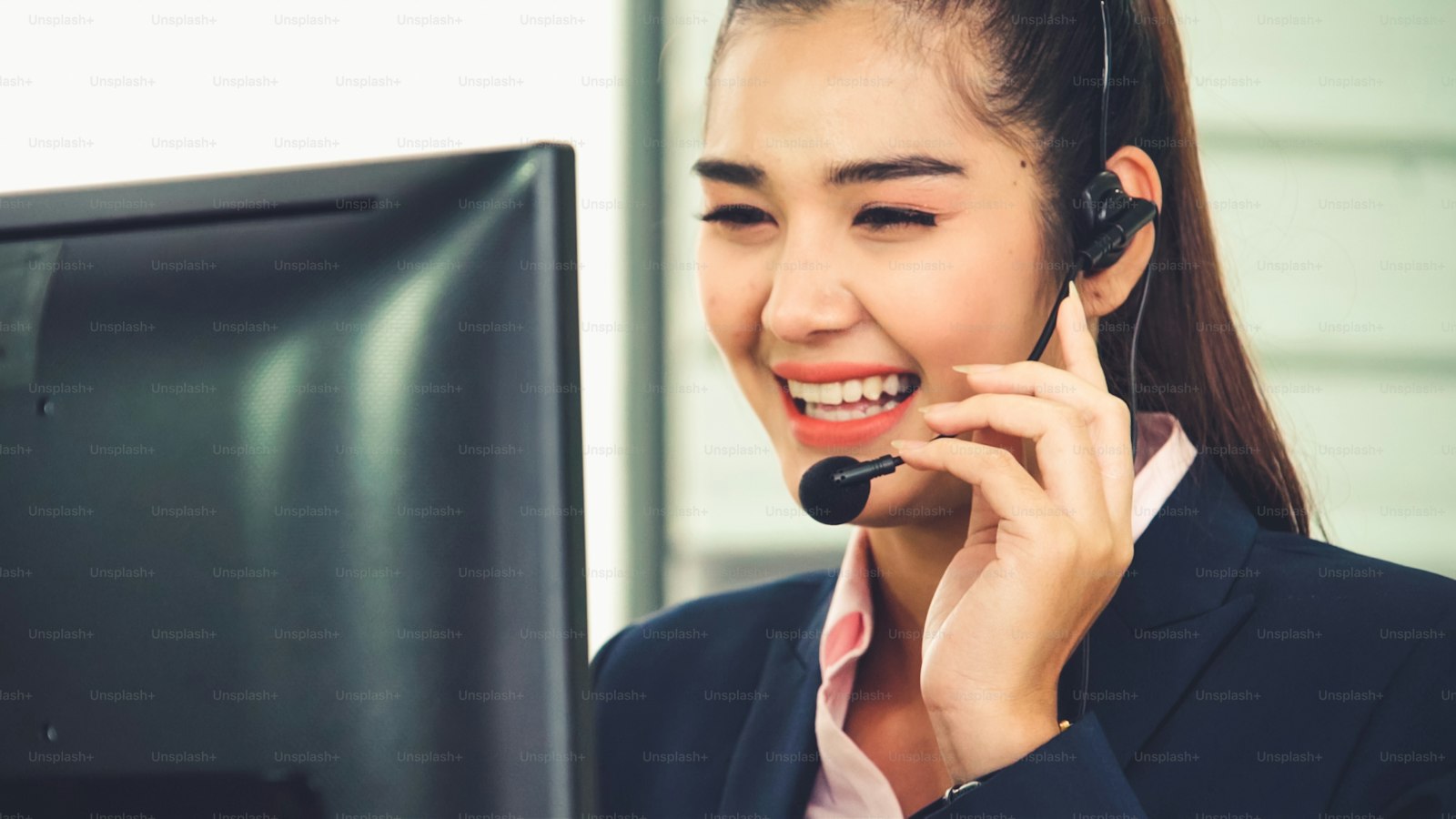 A smiling adviser wearing a headset at her desk